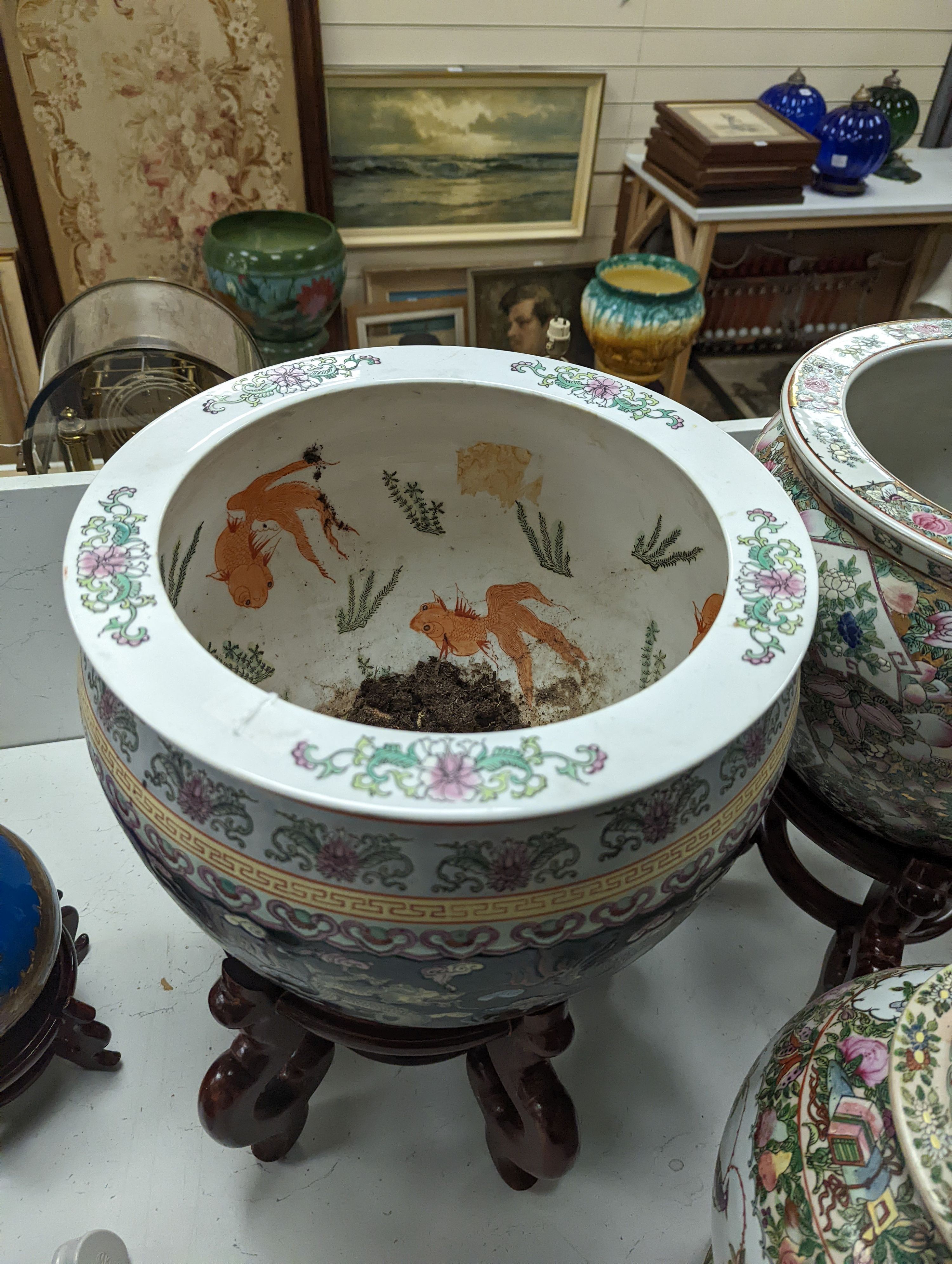 A pair of Chinese fish bowls on hardwood stands and a similar jar and cover, Fish bowls and stands 54 cms high.
